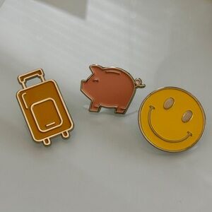 DEAL - Set of Three Enamel Pins - Luggage, Piggy Bank, and Smiley Face